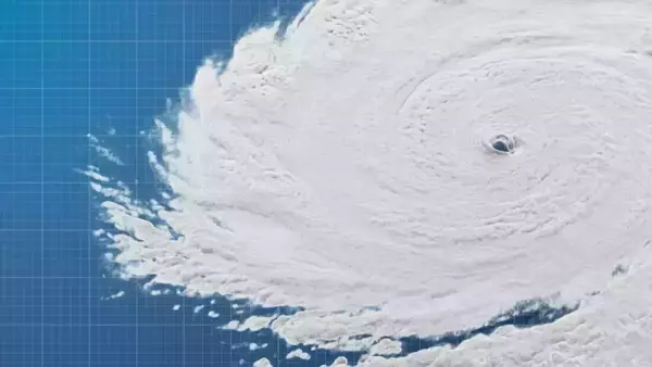 Satellite image of a hurricane with a distinct eye over a blue gridded map.
